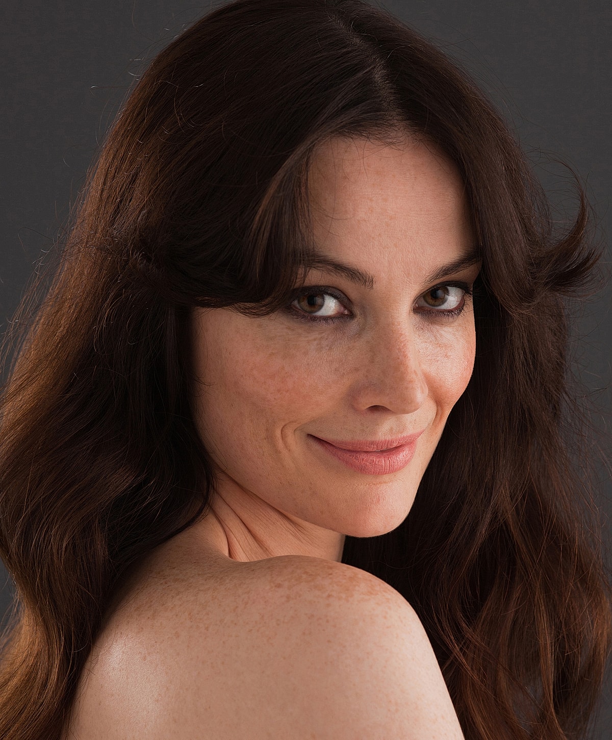 Smiling woman with long, wavy brown hair.