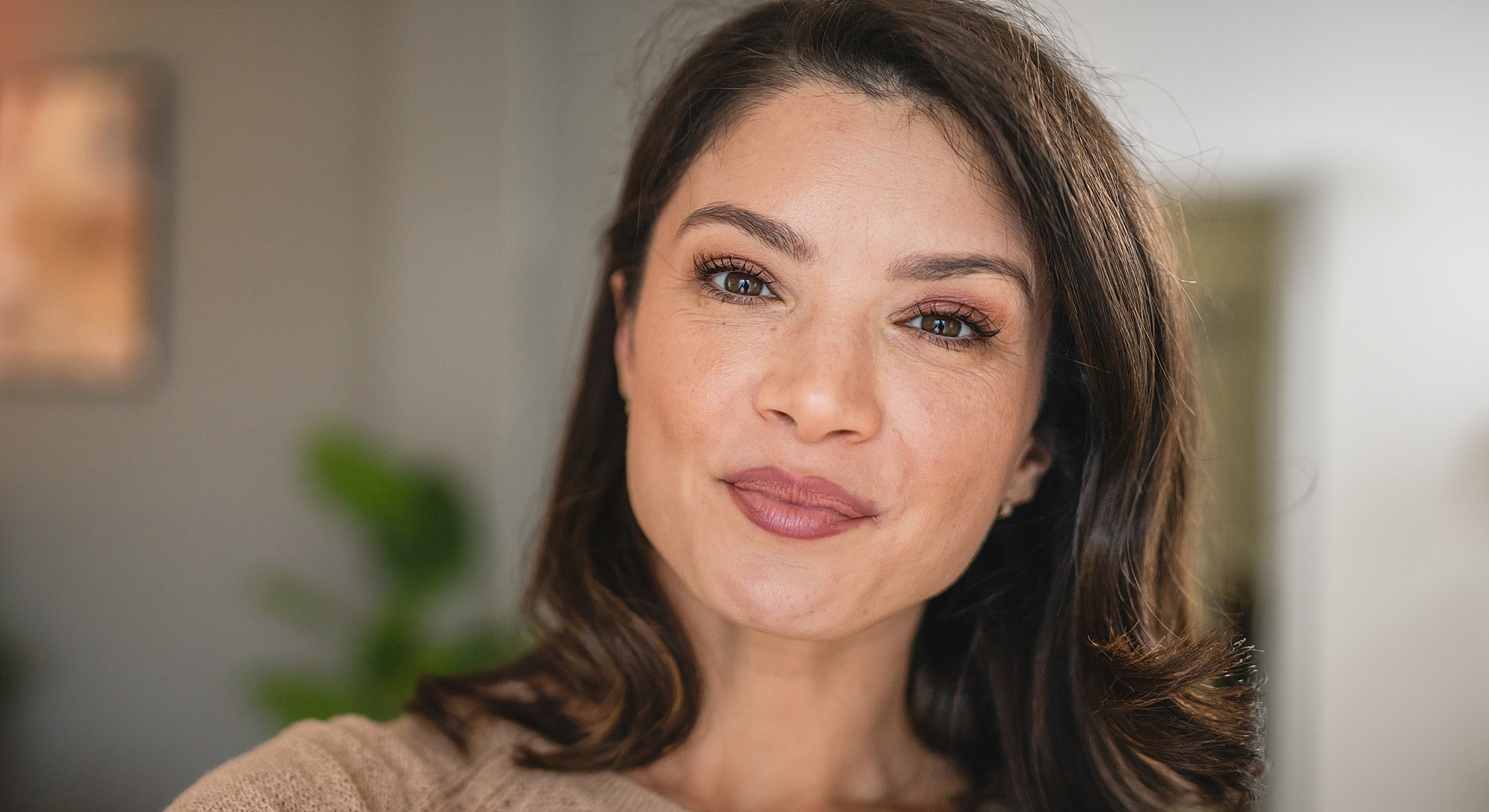 Smiling woman with medium-length brown hair indoors.